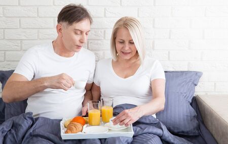 Romantic happy couple having breakfast in bedの写真素材