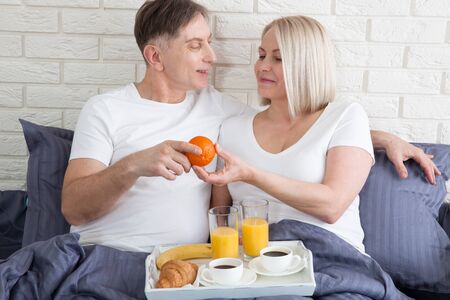 Good morning. Healthy breakfast in bed. Beautiful love couple is sitting in bed before having breakfast.の写真素材