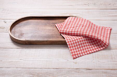 Black plate or tray, or pizza board, with tablecloth on wooden table. Top view mockupの写真素材
