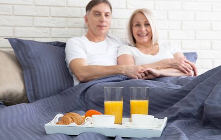 Romantic happy couple having breakfast in bedの写真素材