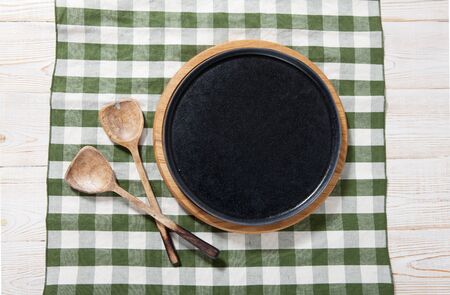 Black plate or tray, or pizza board, with tablecloth on wooden table. Top view mockupの写真素材