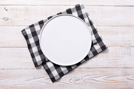 Black plate or tray, or pizza board, with tablecloth on wooden table. Top view mockupの写真素材