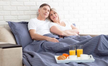 Romantic happy couple having breakfast in bedの写真素材