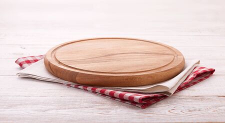 Napkin and board for pizza on wooden desk. Canvas, dish towels on white wooden table background top view mock up. Selective focus.の写真素材