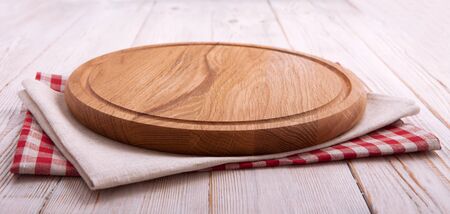 Napkin and board for pizza on wooden desk. Canvas, dish towels on white wooden table background top view mock up. Selective focus.の写真素材