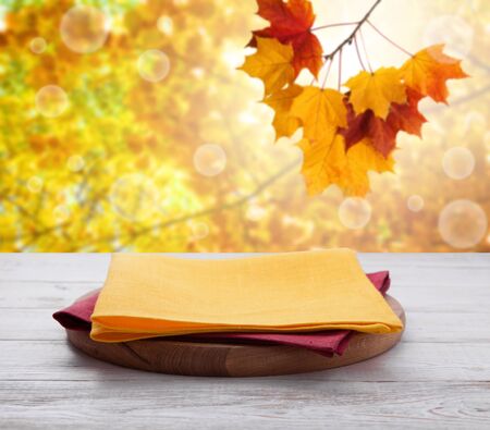 Pizza board with towel on wooden desk. Autumn background. Top view mock up. Selective focus.の写真素材