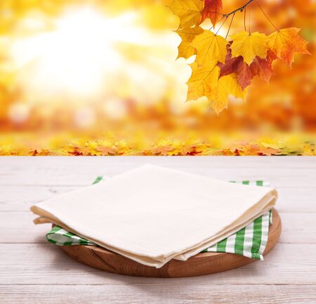 Pizza board with tableclothe on wooden desk. Autumn background. Top view mock up. Selective focus.の写真素材