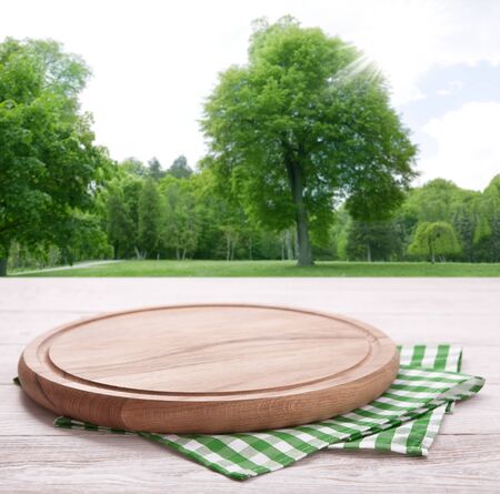 Pizza board, with tablecloth on wooden table and summer background. Top view mockupの写真素材