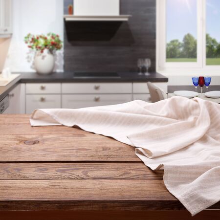 Empty wooden table with tablecloth near the window in kitchen. Napkin close up top view mock up for design. Kitchen rustic background.の写真素材