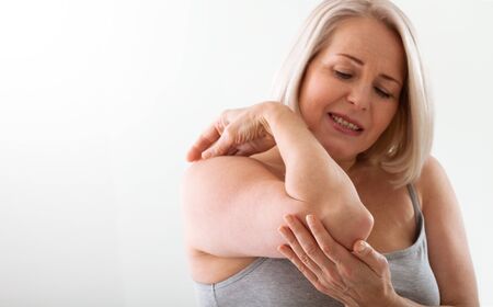 Woman with pain in arm, elbow. Pain in the human body, health care concept.の写真素材