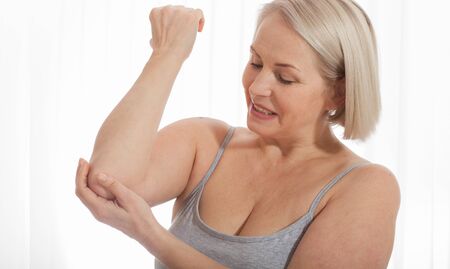 Woman with pain in arm, elbow. Pain in the human body, health care concept.の写真素材