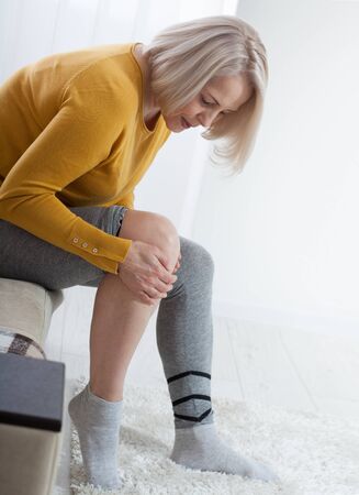 Ankle pain, painful point. Unhappy woman suffering from pain in leg at homeの写真素材