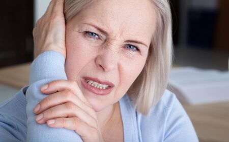 Tinnitus. Closeup up side profile sick female having ear pain touching her painful head.の写真素材