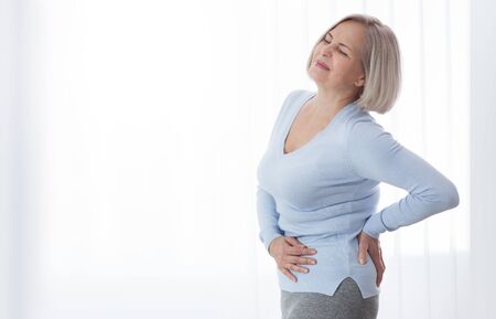 Woman in pain holding her stomach on the right sideの写真素材