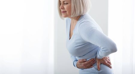 Woman in pain holding her stomach on the right sideの写真素材