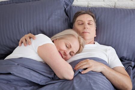Happy couple is lying in bed together. Enjoying the company of each other.の写真素材
