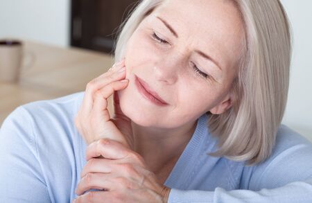 Teeth problem. Woman feeling tooth pain. Closeup of beautiful middle-aged suffering from strong toothache. Attractive female feeling painful toothache. Dental health and care concept. High resolution.の写真素材