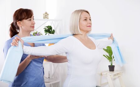 Physiotherapy, sport injury rehabilitation treatment with Resistance Band. Woman having chiropractic back adjustment. Osteopathy, Alternative medicine, pain relief concept.の写真素材