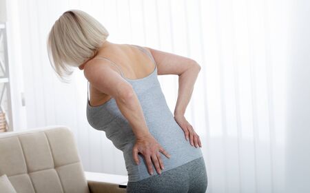 Middle aged woman with pain in the backache and lower back. Concept photo with indicating location of the pain. Health care conceptの写真素材