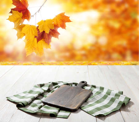 Empty pizza board and table cloth on wooden deck table with napkin. Autumn background.の写真素材