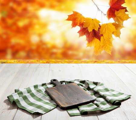 Empty pizza board and table cloth on wooden deck table with napkin. Autumn background.の写真素材