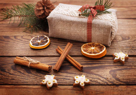 Gift box is festively decorated with Christmas branch on wooden deskの写真素材