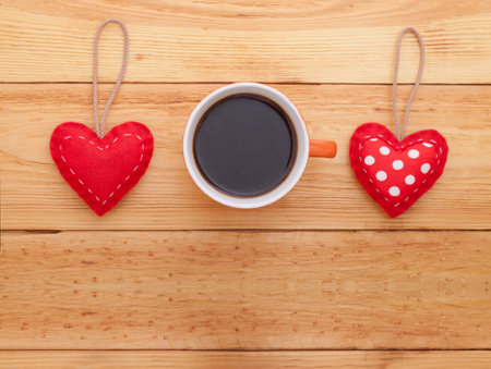 Red hearts and cup of coffee on wooden tableの写真素材