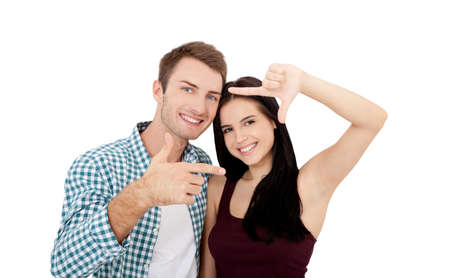 Beautiful young lovers are joining and smiling, making a frame from their handsの写真素材