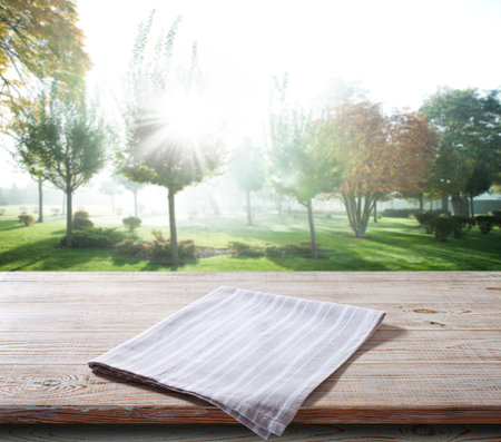 White napkin, table cloth on wooden deck mockup. Summer landscape background