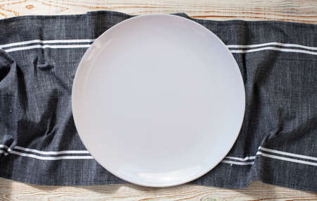 Empty white plate and napkin on light gray table, flat lay topの写真素材