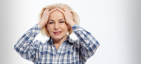 Closeup portrait of beautiful mature old senior mid aged woman suffering from headache migraine massaging temples in menopause period illness, worriedの写真素材