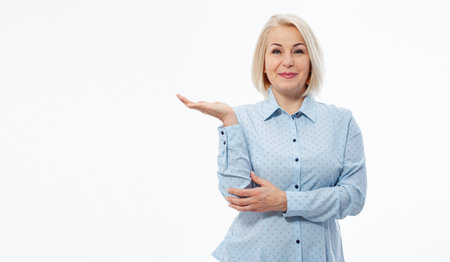 Photo of happy woman standing isolated over white wall background. Looking camera showing copyspace pointing.の写真素材