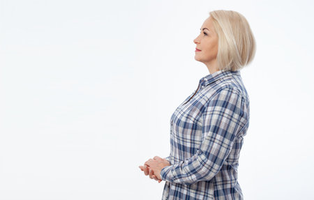 Attractive middle aged woman with folded arms in profile isolated on white backgroundの写真素材