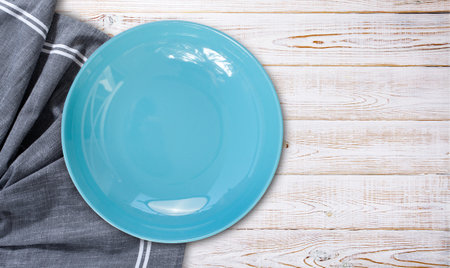 Empty blue plate and tablecloth on wooden desk, flat layの写真素材