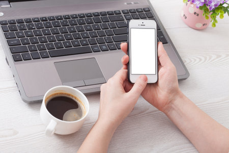Woman holds smartphone white phone in the workplace in the room. Woman using a mobile phone for work.の写真素材