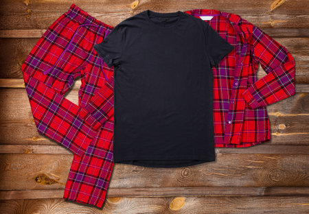 Blank black t-shirts for the whole family on the background of bright pajamas on a wooden backgroundの写真素材