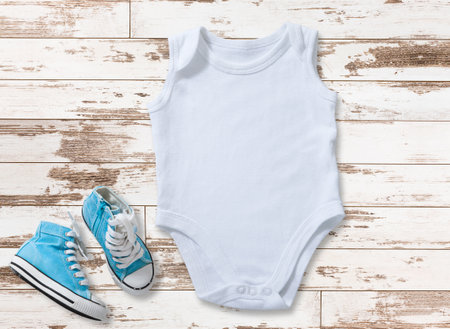 Mockup of white baby bodysuit on white wood background with sneakers. Blank baby clothes template in farmhouse style, flat lay.の写真素材