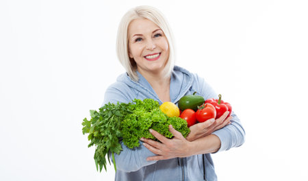 Happy woman with blond hair and beautiful smile holds a vegetables and herbs red pepper and green lettuce in her hands for a healthy diet. The concept of healthy eating vegetables.の写真素材