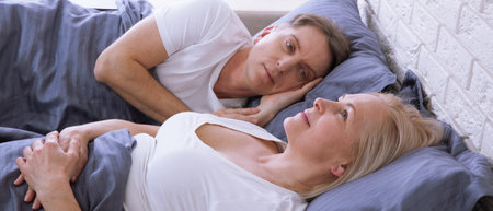 Unhappy middle aged couple in bedroom at homeの写真素材