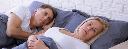 Unhappy middle aged couple in bedroom at homeの写真素材