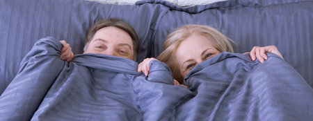 Mature couple together in bed. Pandemic isolation concept Selective focus.の写真素材
