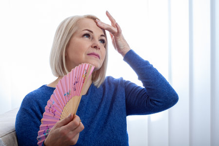 Mature woman experiencing hot flush from menopauseの写真素材