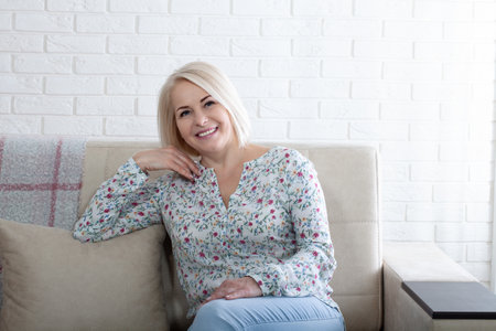 Happy woman relaxing on her couch at home in the sitting room. Age is just a number and I love every minute of it.の写真素材