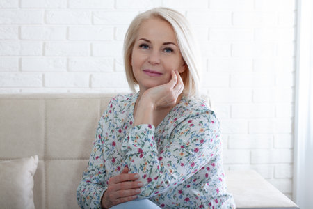 Happy mature woman relaxing on her couch at home in the sitting roomの写真素材