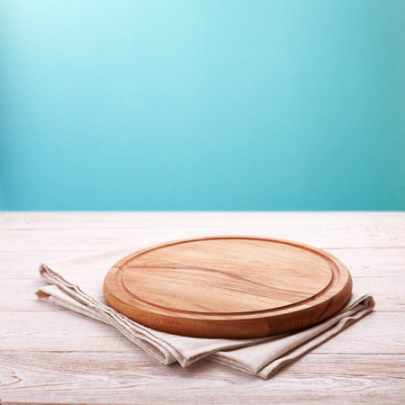 Get an exquisite experience with this high-quality wooden pizza board and napkin. Blue pastel background top view mock up.の写真素材