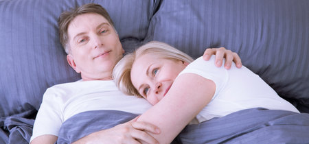 Mature heterosexual beautiful couple lying on bed in bedroom at homeの写真素材