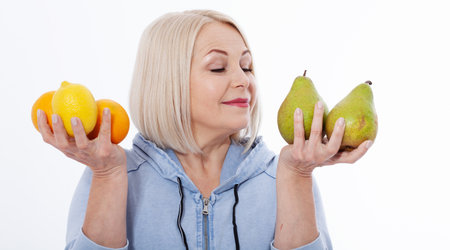 Happy woman with blond hair and beautiful smile holds two oranges, lemon and a pears in her hands for a healthy diet with vitaminswith. Concept healthy food fruitsの写真素材