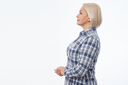 Attractive middle aged woman with folded arms in profile on white backgroundの写真素材