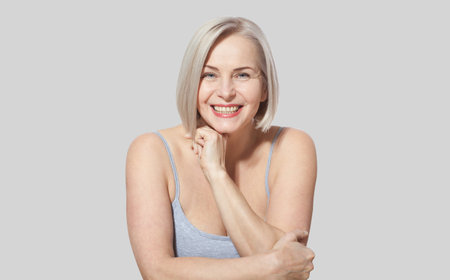 A stunning middle-aged blonde woman displays her exquisitely well-maintained face. Close-up shot. Authentic visuals showcasing her unique perfections.の写真素材