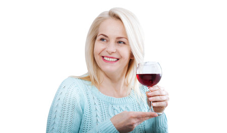 Happy woman holds a glass of red wine and looks relaxed past the camera isolated on white.の写真素材